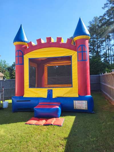Red, yellow, and blue Castle Bounce House photographed in a sunny backyard