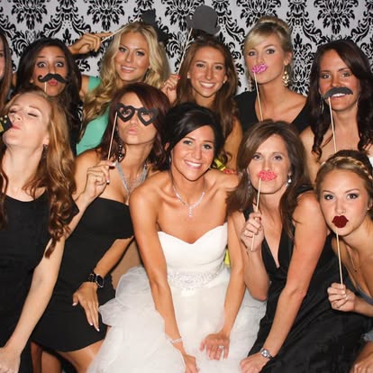 Wedding guests posing together with playful photo booth props.